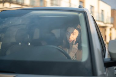 Telefonda konuşan ve araba süren genç bir kadın.