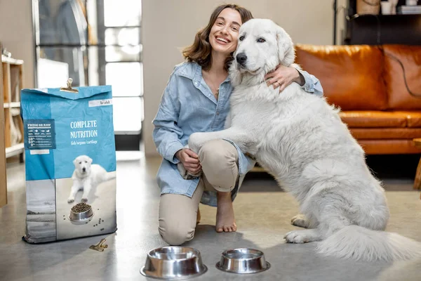 Mujer alimentando a perro con una comida seca en casa —  Fotos de Stock