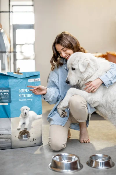 Mujer alimentando a perro con una comida seca en casa —  Fotos de Stock