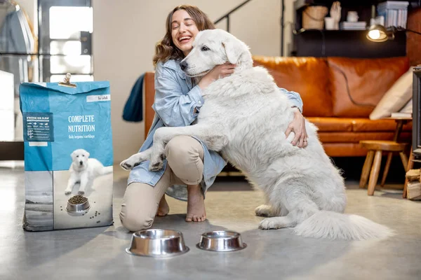 Женщина кормит собаку сухой едой дома — стоковое фото