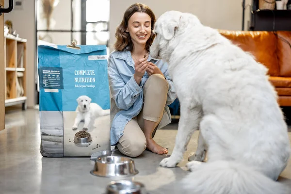 Femme nourrit un chien de nourriture sèche à la maison — Photo