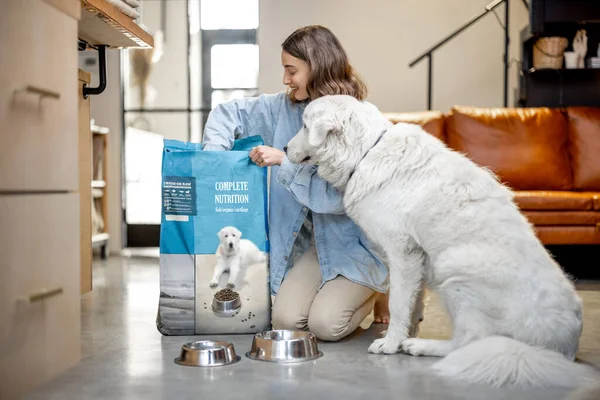 Mujer alimenta a un perro con comida seca en casa — Foto de Stock