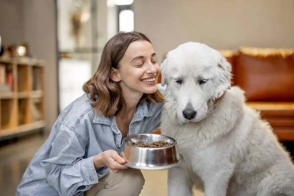 Mujer alimentando a perro con una comida seca en casa —  Fotos de Stock