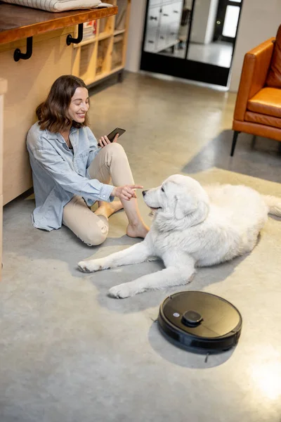 Mulher relaxada com cão e aspirador robótico — Fotografia de Stock