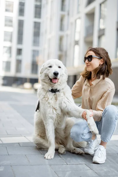 Kvinna går med sin stora vita hund på gatan — Stockfoto