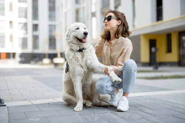 Femme marchant avec son gros chien blanc dans la rue — Photo