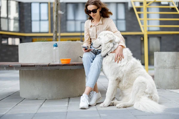 Femme assise sur banc avec animal de compagnie dans la cour de la résidence — Photo