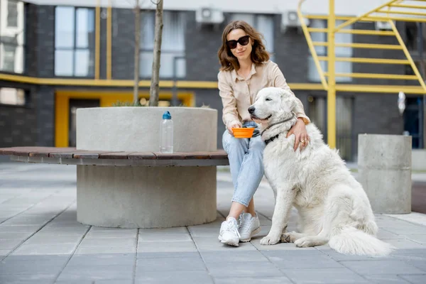 Kvinna ger ett vatten i en skål till sin hund — Stockfoto