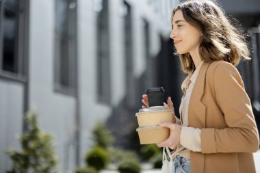 Kadının biri ofis binasının yanındaki merdivenlerde öğle yemeği yiyor.