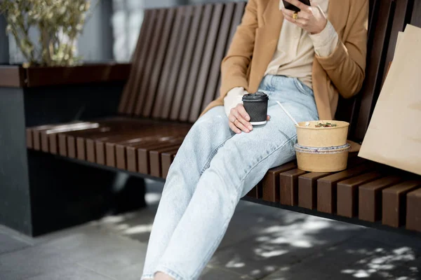 Mujer tienen almuerzo al aire libre en el banco cerca del edificio de oficinas — Foto de Stock