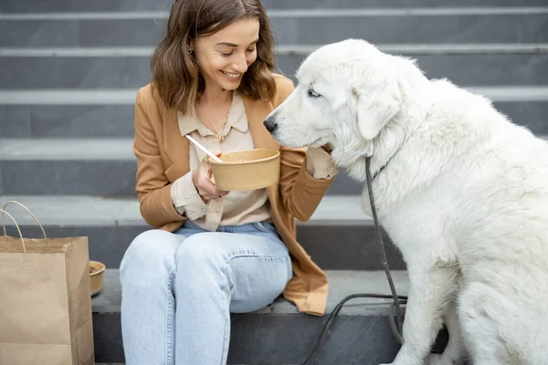 Kvinna äter lunch utomhus med hund — Stockfoto