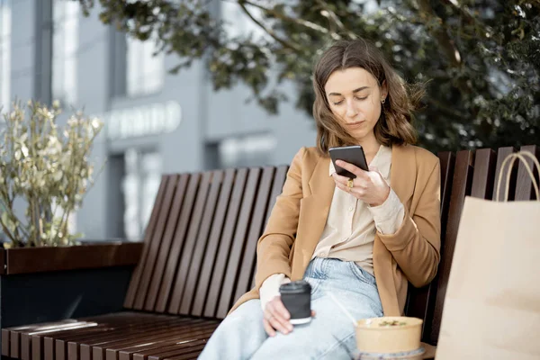 Mujer tienen almuerzo al aire libre en el banco cerca del edificio de oficinas — Foto de Stock