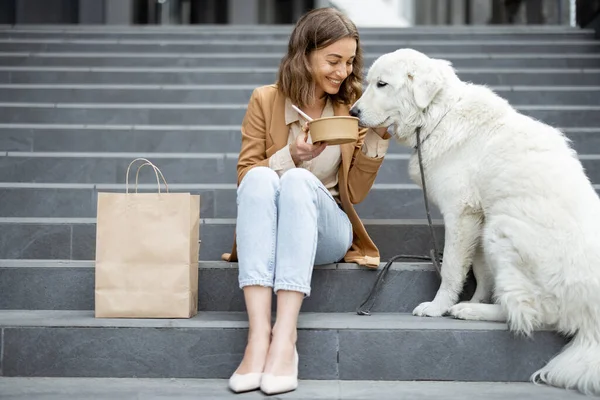 Kvinna äter lunch utomhus med hund — Stockfoto