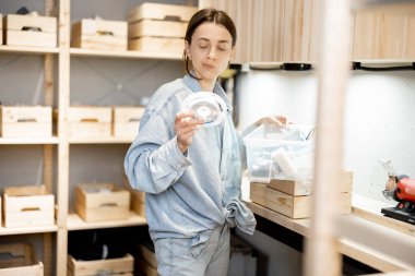 Kadın atölyede bazı aletleri arıyor.