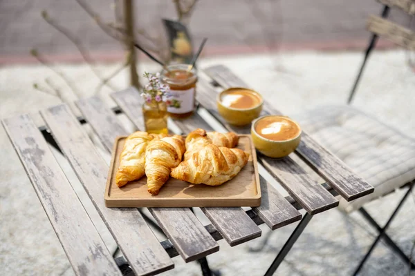 Croissants sous la cloche de verre avec des tasses de café — Photo