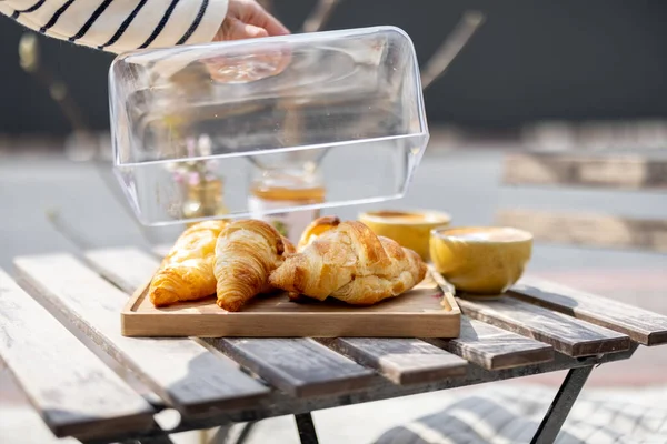 Croissants under the glass cloche with cups of coffee — Stock Photo, Image