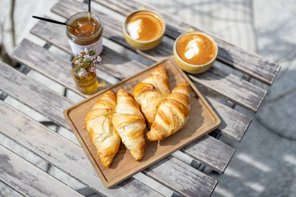 Croissants under the glass cloche with cups of coffee — Stock Photo, Image