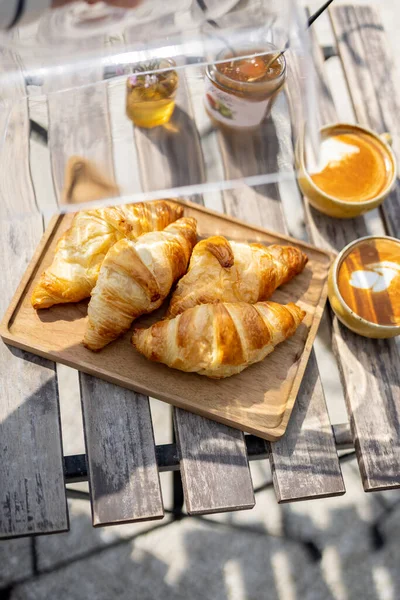 Croissants under the glass cloche with cups of coffee — Stock Photo, Image