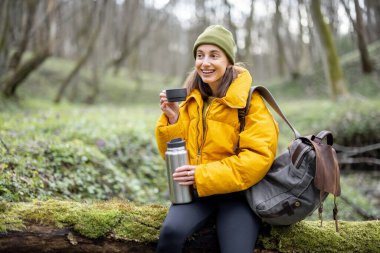 Ormanda termostan sıcak çay içen bir kadın