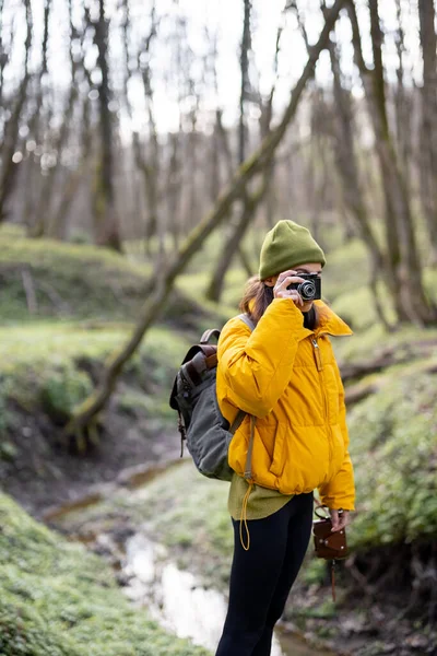 Žena v turistickém oblečení s kamerou v lese — Stock fotografie