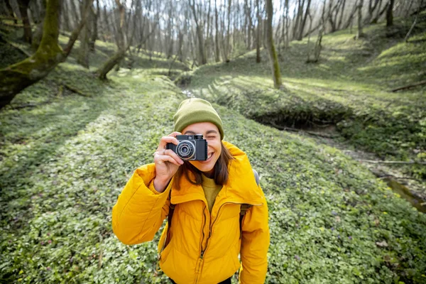 Vrouw in wandelkleding met camera in het bos — Stockfoto