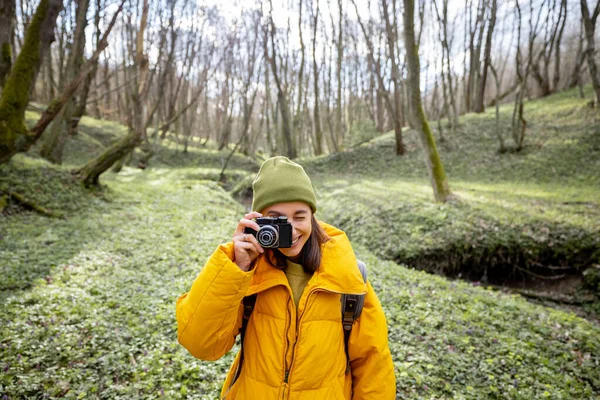 Vrouw in wandelkleding met camera in het bos — Stockfoto