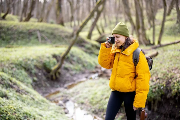 Mulher em roupas de caminhada com câmera na floresta — Fotografia de Stock