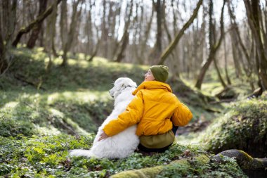 Genç bir kadın köpekle ormanda vakit geçirir..