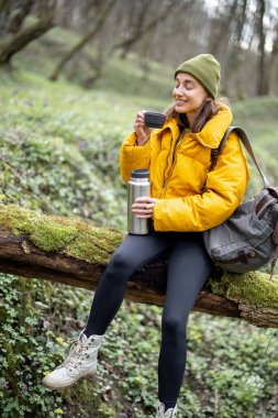Ormanda termostan sıcak çay içen bir kadın