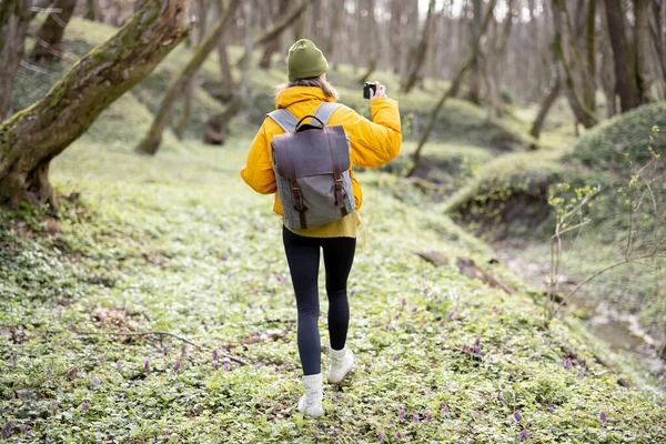 Kvinna i vandringskläder med kamera i skogen — Stockfoto
