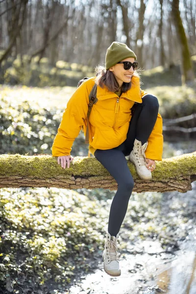 Femme assise sur un arbre au-dessus de la rivière dans la forêt — Photo