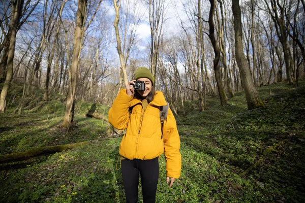 Kvinna i vandringskläder med kamera i skogen — Stockfoto