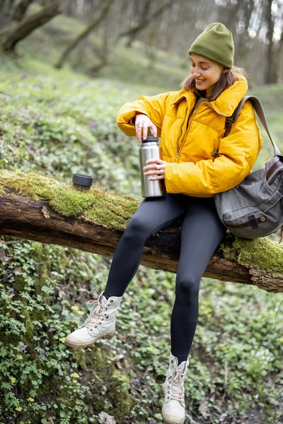 Mulher beber chá quente de garrafa térmica na floresta — Fotografia de Stock