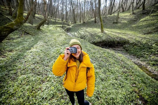 Femme en vêtements de randonnée avec caméra en forêt — Photo