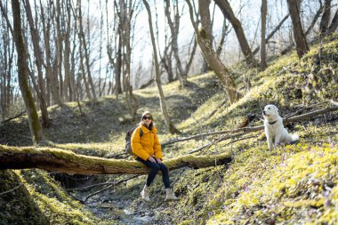 Genç bir kadın köpekle ormanda vakit geçirir..