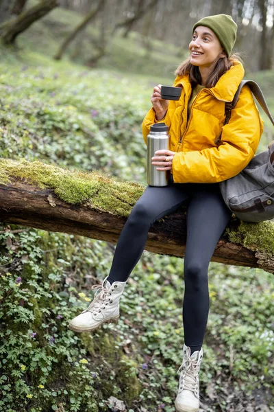 Mulher beber chá quente de garrafa térmica na floresta — Fotografia de Stock