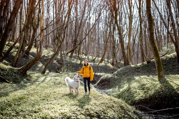 Young woman spend time together with dog in forest.