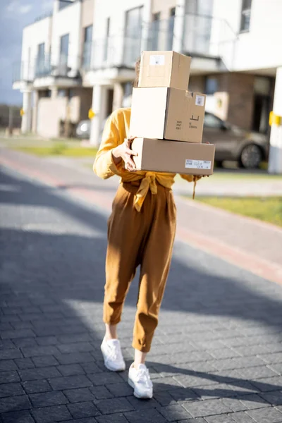 Жінка тримає посилки на вулиці перед будинком — стокове фото