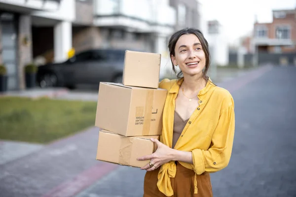 Woman holding parcels on the street in front of the house