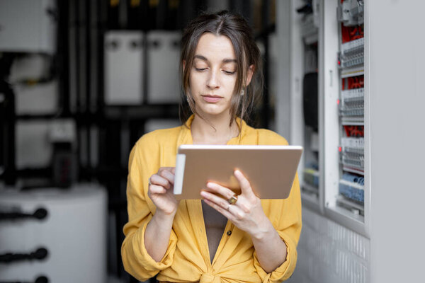 Housewife with tablet in the boiler room at home