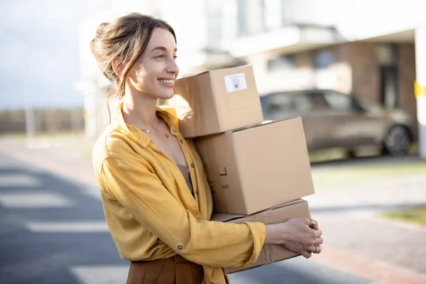 Жінка тримає посилки на вулиці перед будинком — стокове фото