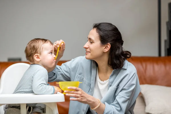 Matka krmí ji jeden rok chlapeček s lžičkou. — Stock fotografie