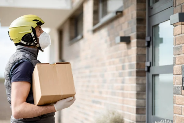 Kurier mit Maske und Handschuhen hält Paketkasten — Stockfoto