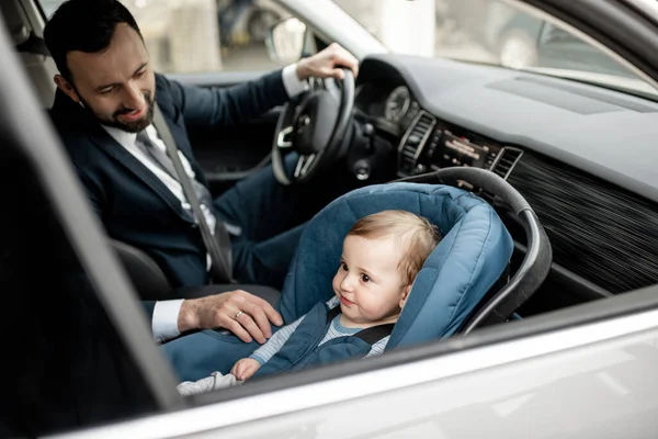 Padre conduciendo en el trabajo con el bebé sentado en el asiento de coche moderno. — Foto de Stock