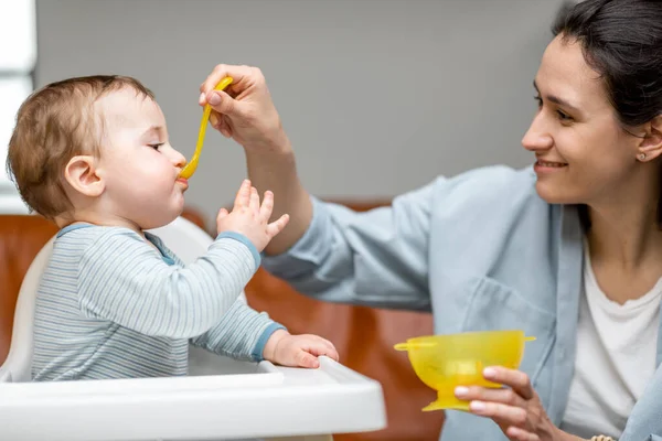 Matka krmí ji jeden rok chlapeček s lžičkou. — Stock fotografie