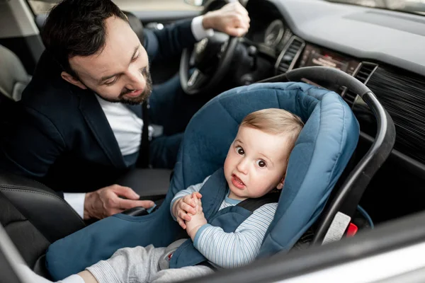 Padre conduciendo en el trabajo con el bebé sentado en el asiento de coche moderno. — Foto de Stock