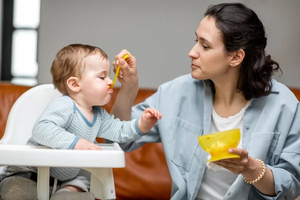 Mother feeding her one year baby boy with a spoon. — Stock Photo, Image
