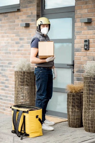 Kurier mit Maske und Handschuhen hält Paketkasten — Stockfoto