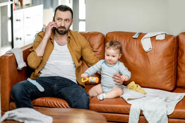 Müder Vater stillt ein Neugeborenes, während er auf dem Sofa sitzt — Stockfoto