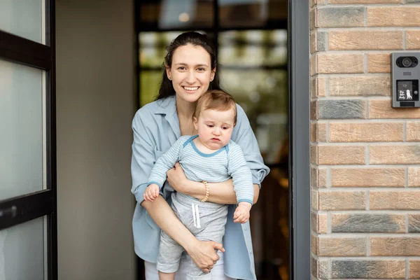 Žena v domácnosti s novorozeně dítě pobyt před vchodovými dveřmi — Stock fotografie